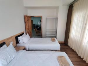 a hotel room with two beds and a hallway at Happy apartment in Thimphu