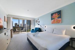 a bedroom with a large white bed and a blue chair at Beautiful Studio Apartment with Ocean Views in Gold Coast