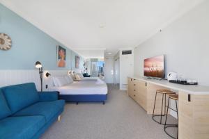a bedroom with a bed and a blue couch at Beautiful Studio Apartment with Ocean Views in Gold Coast