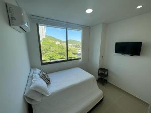 een kleine slaapkamer met een bed en een raam bij Apto Samaria Club de Playa, encanto del mar in Santa Marta