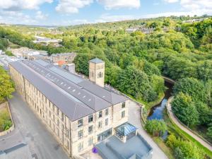 an overhead view of a building with a river and trees at Hayy ApartHotels Stanley Mills in Huddersfield