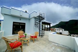 a patio with chairs and a table on a roof at Vrindhavan Mist City Resorts in Kanthalloor