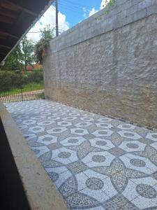 um pátio em azulejo com uma parede de pedra e um piso de azulejo em Chácara Deh* em Bragança Paulista