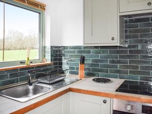 cocina con fregadero y ventana en Norville Lodge, en Heathfield