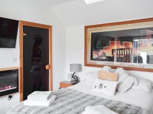 1 dormitorio con cama blanca y chimenea en Norville Lodge, en Heathfield