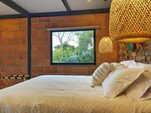 a bedroom with a bed with a brick wall and a window at Gulupa Ecolodge in Jardin