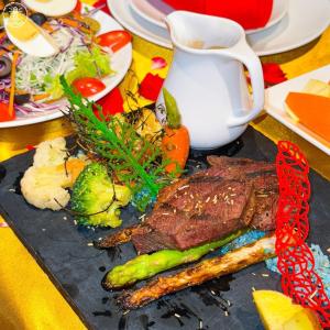 Premier Pearl Hotel Vung Tau في فنغ تاو: طبق من الطعام مع شريحة لحم وخضروات على طاولة