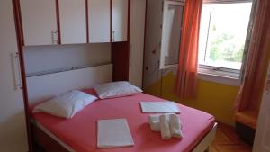 - une chambre avec un lit rose et des serviettes dans l'établissement Apartments by the sea Tisno, Murter - 13588, à Tisno