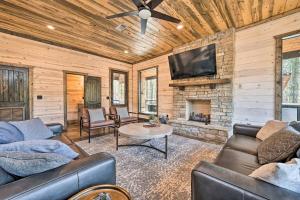 a living room with leather furniture and a stone fireplace at Family Getaway 10-Bed Cabin w Hot tub & Firepit in Broken Bow