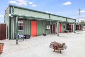 a green building with red doors and a chair at Casas Coastal Experience Cabin C in Rockport