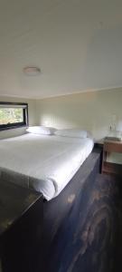 ein großes weißes Bett in einem Zimmer mit Fenster in der Unterkunft Tiny house Alto bosque in Pucón