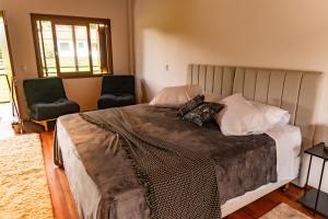 1 dormitorio con 1 cama grande y 2 sillas en Invernada Blessmann en Vespasiano Corrêa