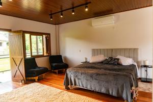 a bedroom with a bed and two chairs at Invernada Blessmann - Hotel Fazenda in Vespasiano Corrêa