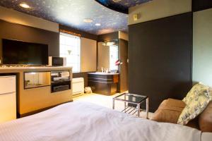 a bedroom with a bed and a tv and a table at ホテル森のしずく in Katsura
