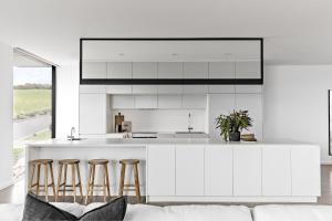 a kitchen with white cabinets and bar stools at Hamilton Gerringong in Gerringong