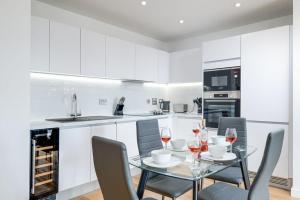 een keuken met een glazen tafel met stoelen en wijnglazen bij Apollo Luxury - Netflix - Fast WIFI- FREE PARKING in Birmingham