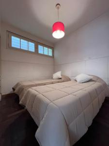 a large bed in a white room with a red light at Departamento PH 4 ambientes La perla a 5 cuadras de playa in Mar del Plata
