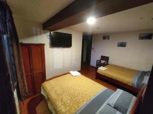 a room with two beds and a flat screen tv at HOSTAL WALDORF.EC in Baños