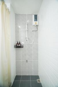 a shower in a bathroom with black and white tiles at Mitr Inn Mrt Samyot Station - The Grand Palace in Bangkok