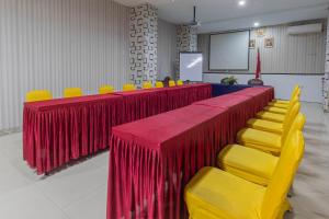 una sala de conferencias con mesas y sillas rojas y amarillas en Hotel DMadinah inn Gentan en Solo