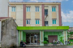 a building with a motorcycle parked in front of it at Hotel DMadinah inn Gentan in Solo