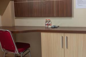 a desk with a chair and two bottles on it at Hotel DMadinah inn Gentan in Solo