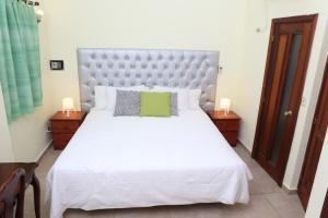 1 dormitorio con 1 cama blanca grande y 2 mesitas de noche en Hotel Aluge, en Santo Domingo