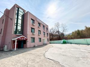 um edifício cor-de-rosa com um parque de estacionamento em frente em Royal motel em Goseong
