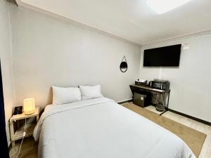 Schlafzimmer mit einem Bett und einem Flachbild-TV in der Unterkunft Royal motel in Goseong