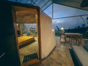 Zelt mit einem Bett und einem Tisch auf einer Terrasse in der Unterkunft Moondock Luxury Camp in Munduk