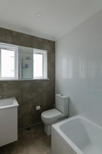 een badkamer met een toilet, een bad en ramen bij Bondi Beachfront Bliss in Sydney +17 foto's