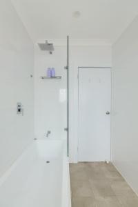 2 witte deuren in een witte kamer met een tegelvloer bij Bondi Beachfront Bliss in Sydney