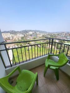 - deux chaises vertes assises sur un balcon avec vue dans l'établissement Cozy Heaven (1-Room)BW, à Guwahati