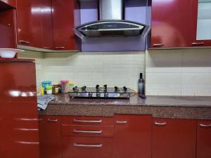 - une cuisine équipée de placards rouges et de plaques de cuisson dans l'établissement Cozy Heaven (1-Room)BW, à Guwahati