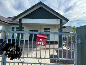 une maison avec une boîte aux lettres rouge sur une clôture dans l'établissement Kahfi Homestay Tanah Merah, Kelantan, à Tanah Merah