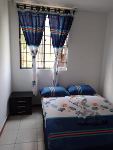 a bedroom with a bed with blue curtains and a window at Apartamento en Villavicencio in Villavicencio