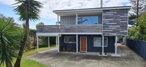 a house with a blue facade with a palm tree at Waikanae Beach Suite Retreat in Waikanae