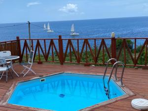 a swimming pool on a deck with a view of the ocean at Bungalows Mathilde-non fumeur in Bouillante