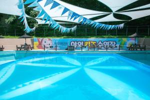 een blauw zwembad met banken en een spandoek bij KensingtonResort JirisanNamwon in Namwon