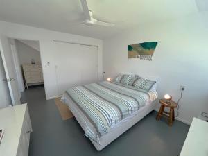 a bedroom with a bed in a white room at Oneroa Village Oasis - Waiheke Escapes in Blackpool