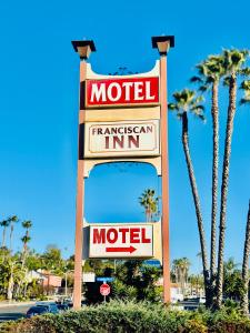 een motelbord voor een aantal palmbomen bij Franciscan Inn Motel in Vista