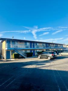 un edificio con dos coches estacionados en un estacionamiento en Franciscan Inn Motel, en Vista