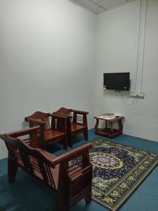 Habitación con sillas, TV y alfombra. en Nawlaa Homestay en Melaka