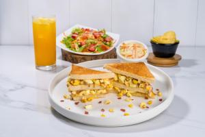 un plato con un sándwich y una ensalada y un vaso de zumo de naranja en Hotel Paraiso, en Portoviejo