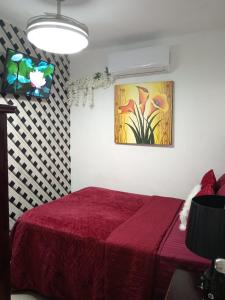 Un dormitorio con una cama roja y una pintura en la pared en Aparta estudio en santiago #1, en Santiago de los Caballeros