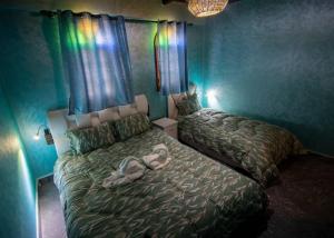 a bedroom with two beds in a room with green walls at Palma Ziz in Aït Athmane