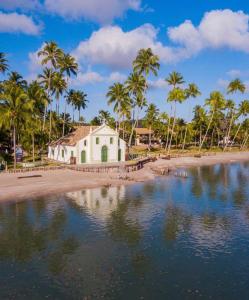 プライア・ドス・カルネイロスにあるCondomínio Meridional Carneirosのヤシの木が茂る海辺の白い建物