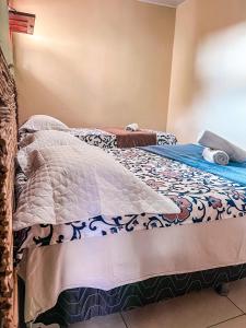 a bed with a comforter on it in a room at Chalé Aconchego dos Milagres in São Miguel dos Milagres