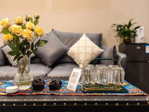 a table with a vase of flowers and glasses on it at Annie Apartment 2505 in Kunming