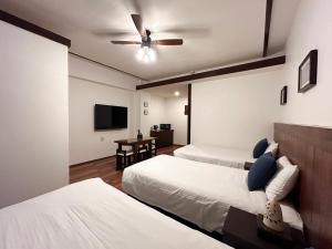 1 dormitorio con 2 camas y ventilador de techo en Pension Sunset Beach, en Nakijin